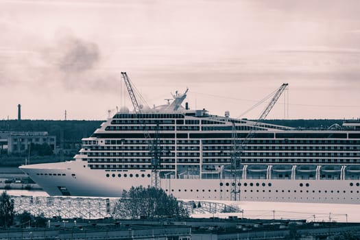 Large cruise liner sailing past the cargo port. Monochrome