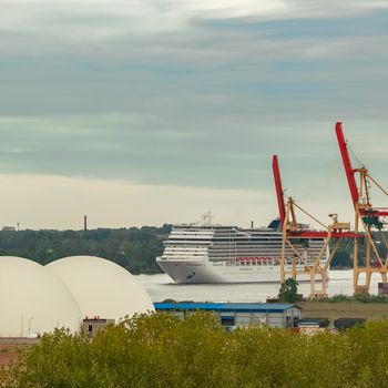 Big white cruise liner sailing past the cargo port