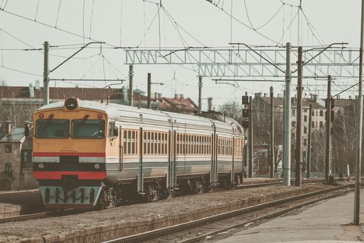 Old yellow passenger diesel train moving at the terminal