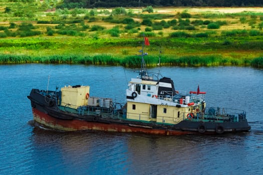 Old tug ship moving to the cargo terminal. Industrial service