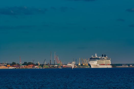 Giant white passenger ship moving past the port on a clear day