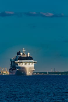 Giant white passenger ship moving past the port on a clear day