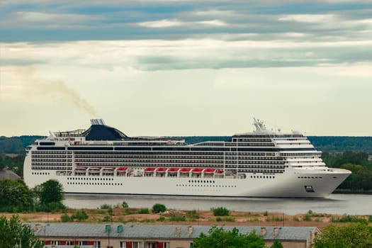 Big white cruise liner sailing past the cargo port