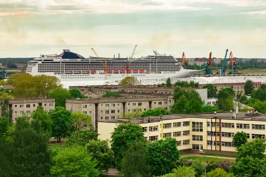 Big white cruise liner sailing past the cargo port