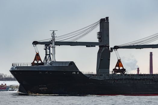 Black bulk carrier sailing to the sea in cold winter