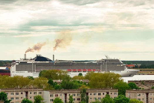 Big white cruise liner sailing past the cargo port