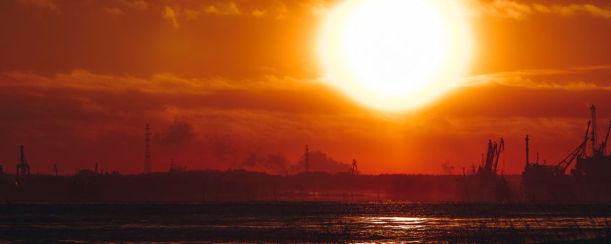 Hot orange winter sunrise against the cargo port