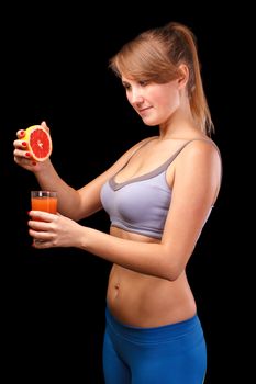 The girl who was engaged in sports, is on a black background with a glass of grapefruit juice.