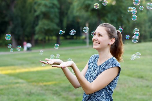 Beautiful girl in the park with soap bubbles.