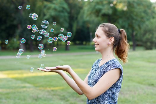 Beautiful girl in the park with soap bubbles.