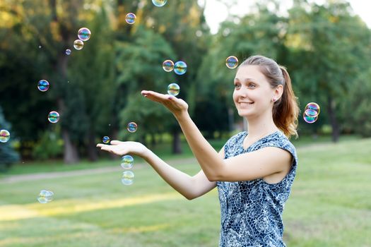 Beautiful girl in the park with soap bubbles.