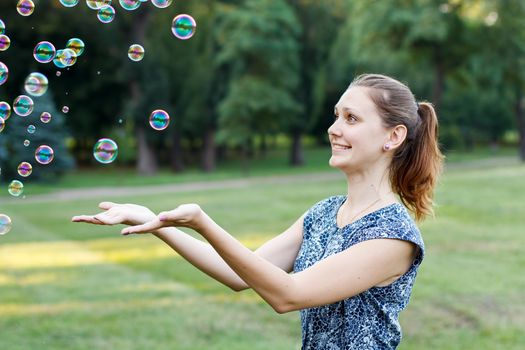 Beautiful girl in the park with soap bubbles.