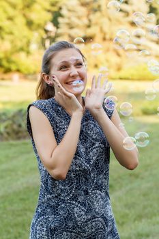 Beautiful girl in the park with soap bubbles.