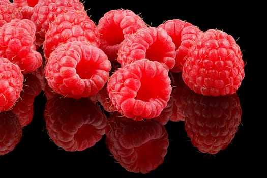 A bunch of ripe raspberries on black background.