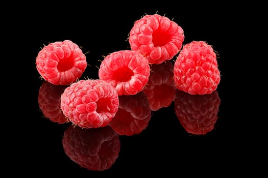 A bunch of ripe raspberries on black background.