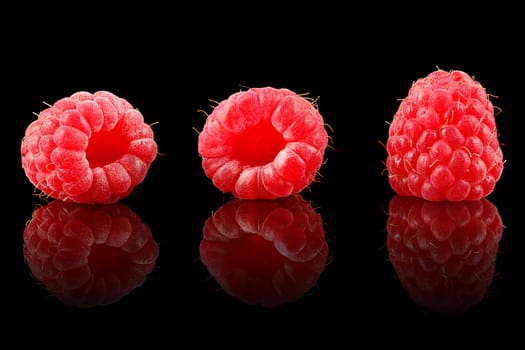 A bunch of ripe raspberries on black background.