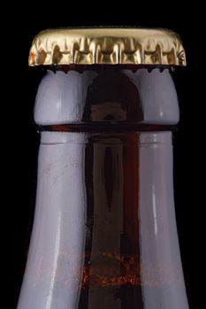 Closed, brown beer bottle on a black background.