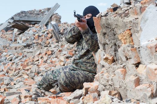 Military camouflage with a rifle on a background of bombed buildings.