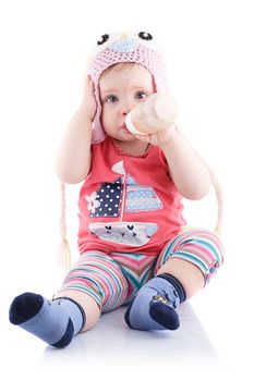 The girl is one year in dress sitting on a white background.