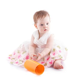 The girl is one year in dress sitting on a white background.