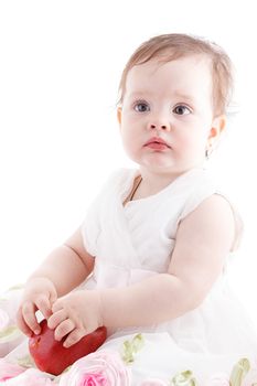 The girl is one year in dress sitting on a white background.