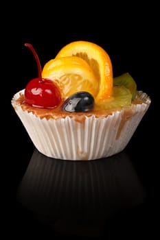 Delicious cake with orange and cherry on a black background.