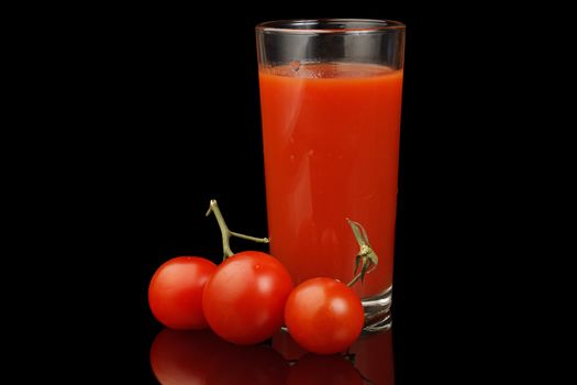 Ripe tomato and tomato juice isolated on a black background.
