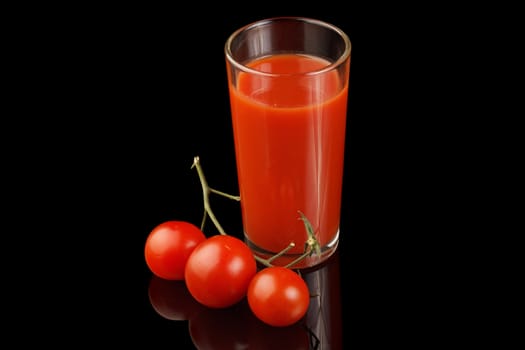 Ripe tomato and tomato juice isolated on a black background.
