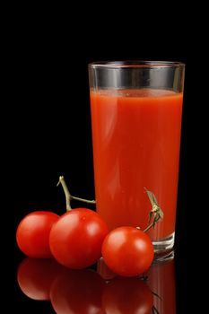 Ripe tomato and tomato juice isolated on a black background.
