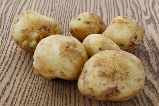 Heap of raw potato lying on the wooden background.