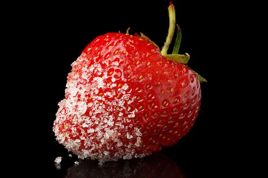 Juicy strawberries in sugar lies on a black background.
