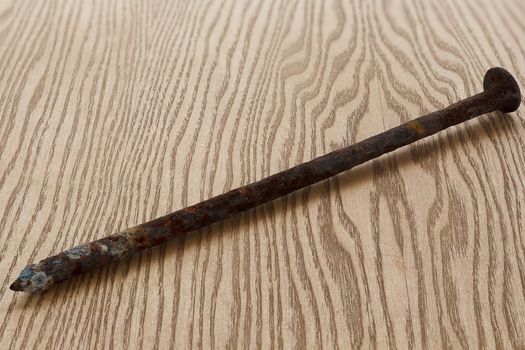 One very old rusty nail on a wooden background.