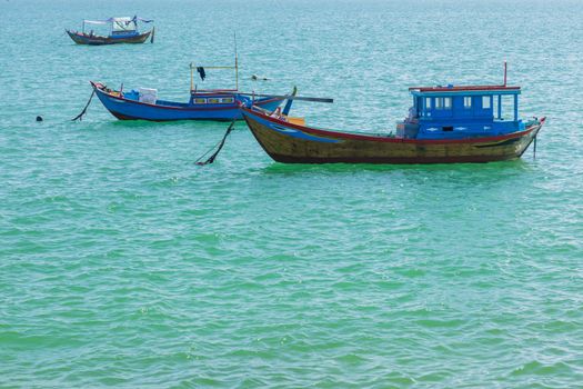 Vietnamese coastline looking out over the south china sea in Nha Trang Vietnam with a turquoise ocean and fishing boats.