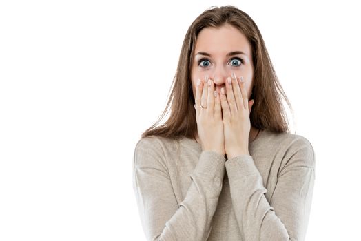 surprised young girl covers her mouth with her hands on a white background isolated