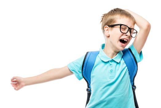 sleepy tired schoolboy with a backpack yawns on a white background in the studio