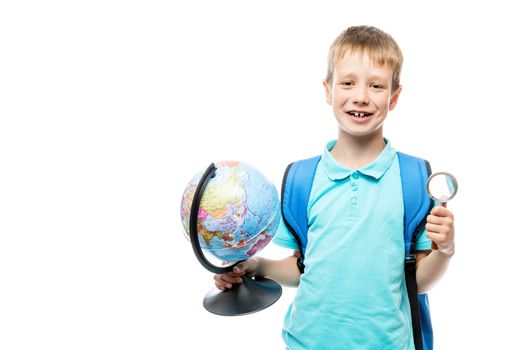 schoolboy with magnifier and globe in hands posing on white background