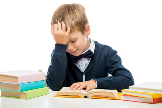 schoolboy at the table reading a book, shooting on a white background