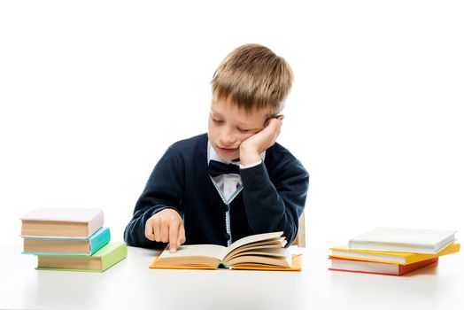 8-year-old schoolboy reading a book at a table, portrait isolated