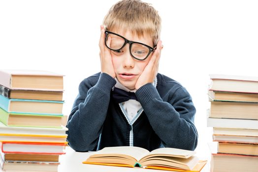 discouraged schoolboy among a pile of books on a white background