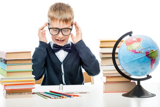 angry schoolboy with books at the table on a white background