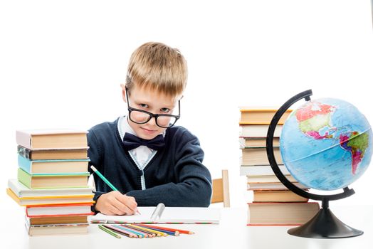 smart schoolboy with literature for reading doing homework at the table, portrait on white background