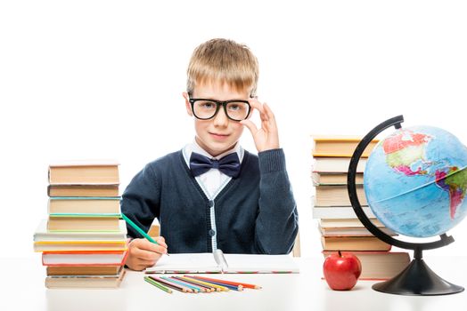 portrait of a happy smart schoolboy at the table with books on a white background