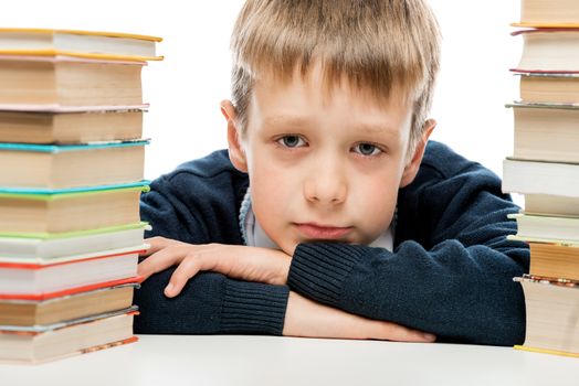 portrait of a tired schoolboy close-up among a pile of books