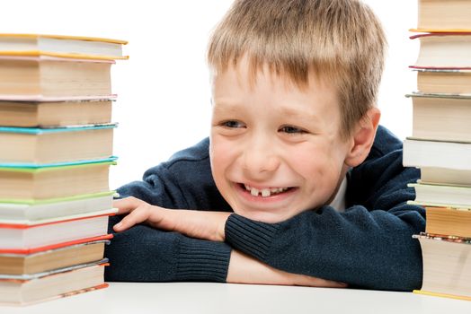 portrait of a laughing schoolboy close-up among a pile of books