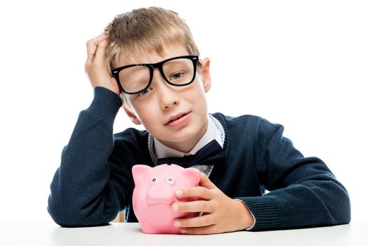 portrait of a tired boy in glasses with a piggy bank pink on a white background
