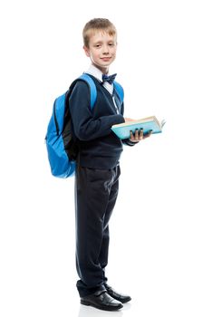 schoolboy with a book and a backpack in the studio on a white background in full length isolated