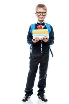 smart schoolboy with a pile of books and a red apple in full length on a white background in the studio