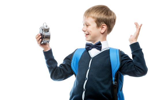 joyful boy in school uniform with an alarm clock on white background