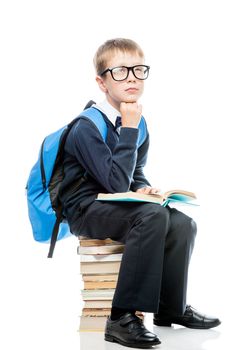 boy sitting on a pile of books on a white background with textbook, portrait isolated