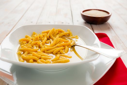 Italian passatelli in brothover a wooden table